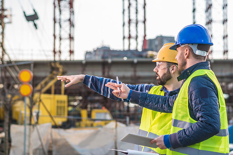 Bau-Software für die Baubranche mit Anbindung an BIM. Baumeister bei der Besprechung auf der Baustelle.